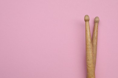 Photo of Two wooden drum sticks on pink background, top view. Space for text