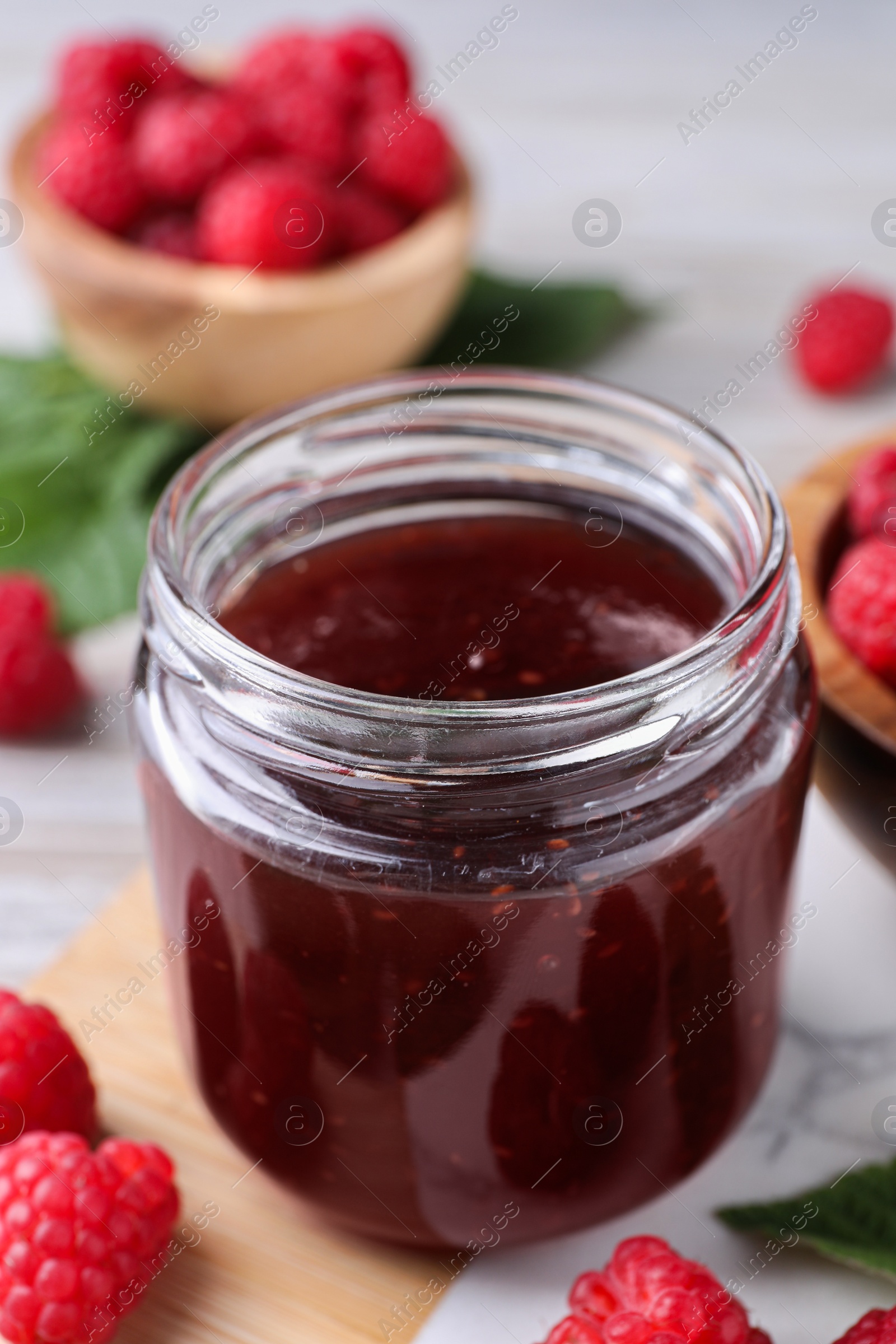 Photo of Jar of delicious raspberry jam and fresh berries on board