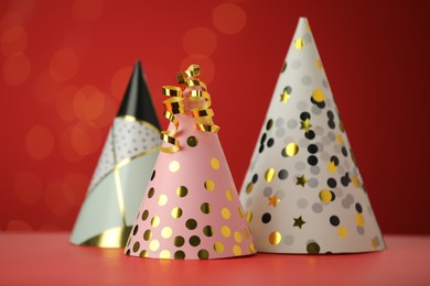 Photo of Beautiful party hats and serpentine streamers on red background