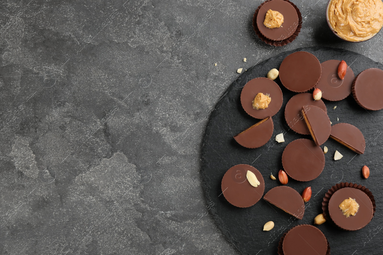 Photo of Flat lay composition with delicious peanut butter cups on grey table, space for text