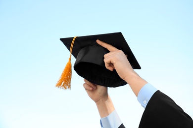 Student with graduation hat and blue sky on background, closeup