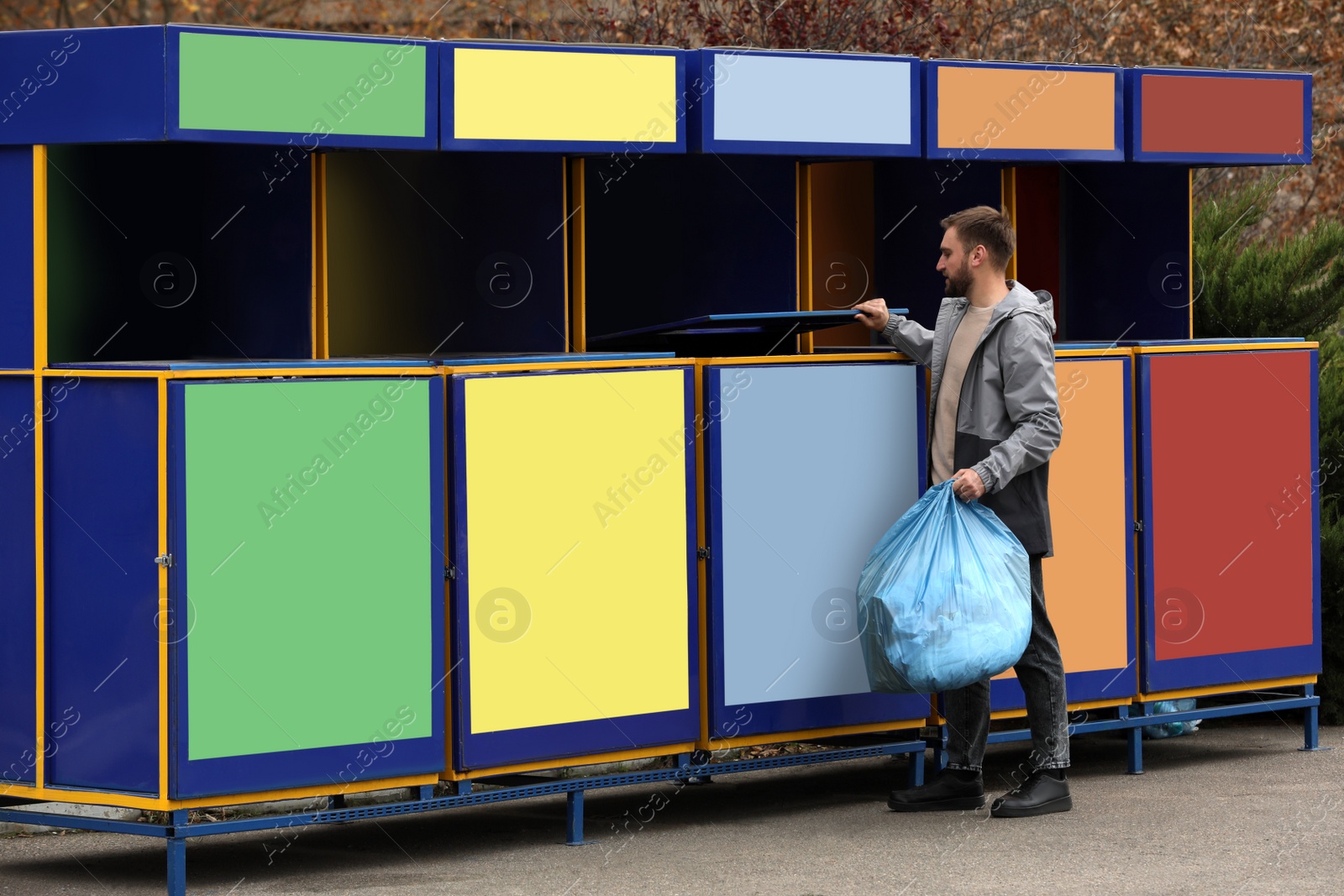 Photo of Man throwing garbage into bin at recycling point outdoors