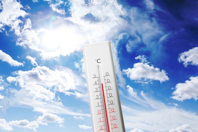 Image of Thermometer showing high temperature against sky with clouds in summer