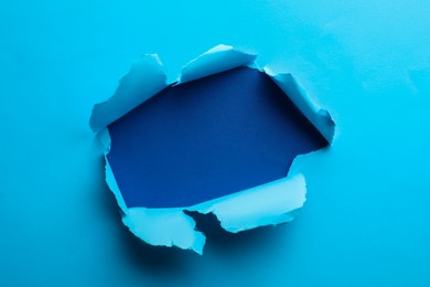 Hole in light blue paper on color background
