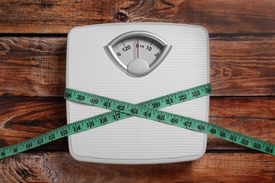 Scales and measuring tape on wooden background, top view. Weight loss concept