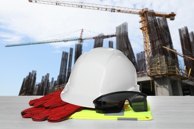 Image of Safety equipment and tools on wooden surface and blurred view of construction site