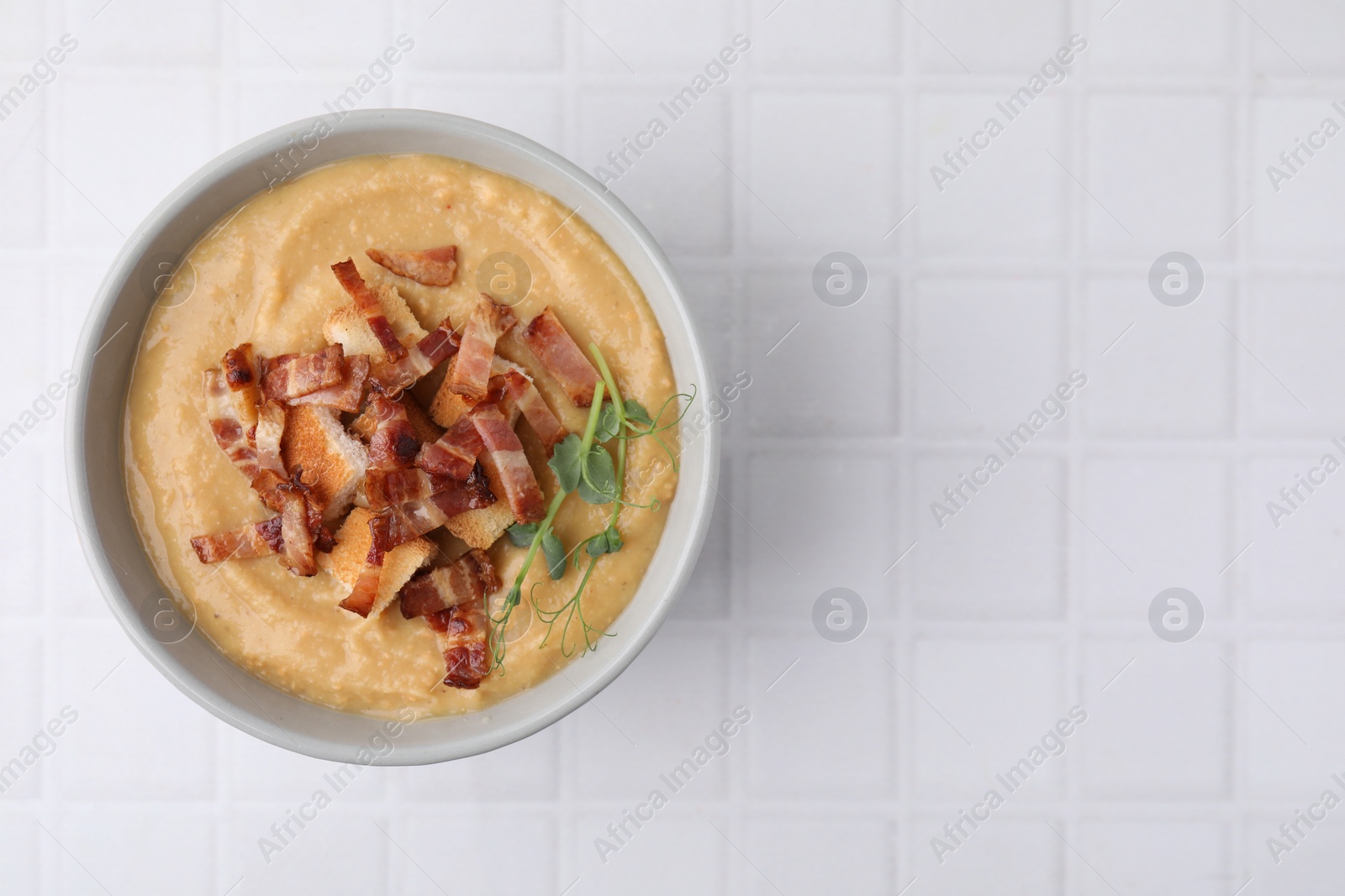 Photo of Delicious lentil soup with bacon and croutons on white tiled table, top view. Space for text