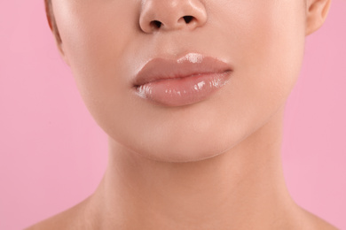 Young woman with beautiful full lips on pink background, closeup