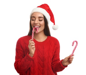 Photo of Young woman in red sweater and Santa hat holding candy canes on white background