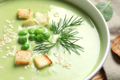 Photo of Fresh vegetable detox soup made of green peas with croutons in dish, closeup