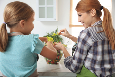 Mother and daughter cooking salad together in kitchen