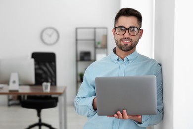 Happy young programmer with laptop in office