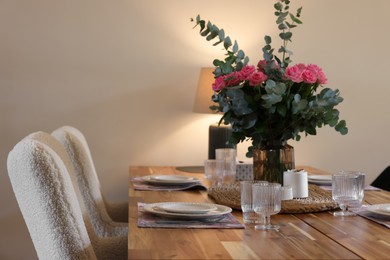 Beautiful table setting with bouquet indoors. Roses and eucalyptus branches in vase