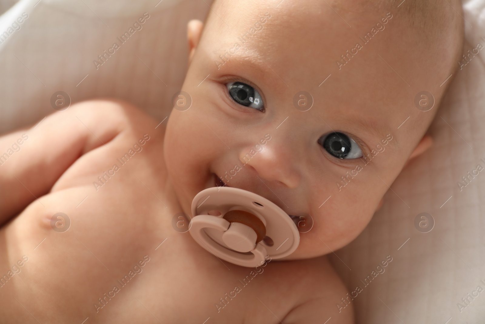 Photo of Cute little baby with pacifier lying on soft blanket, top view