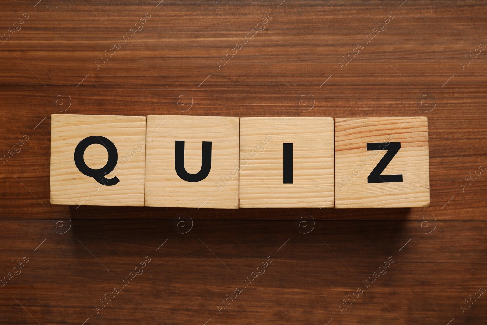 Photo of Cubes with word Quiz on wooden table, flat lay