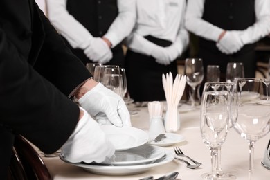 Man wearing formal suit teaching trainees in restaurant, closeup. Professional butler courses