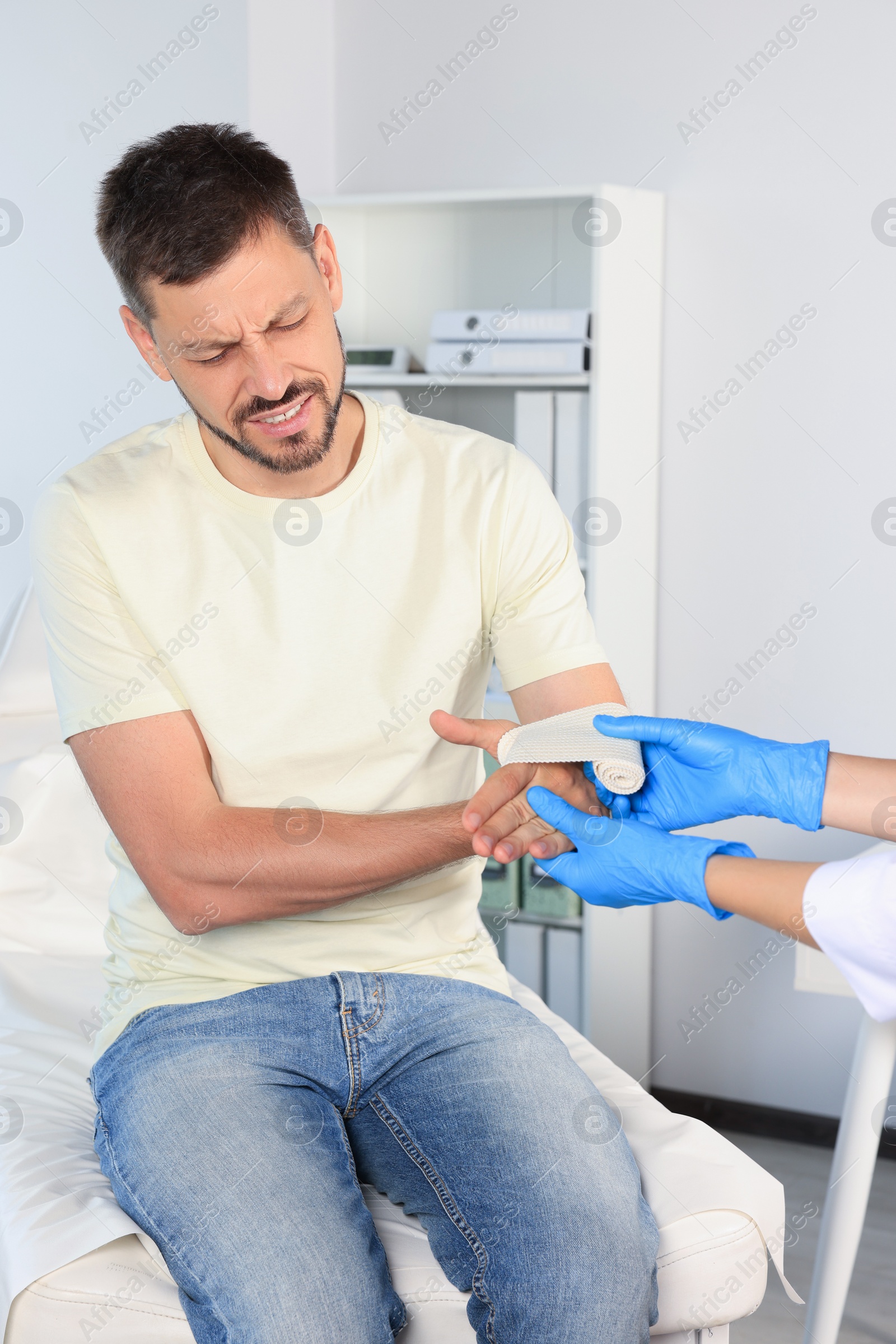 Photo of Doctor applying medical bandage onto patient's hand in hospital