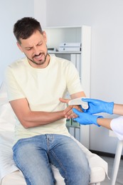 Doctor applying medical bandage onto patient's hand in hospital