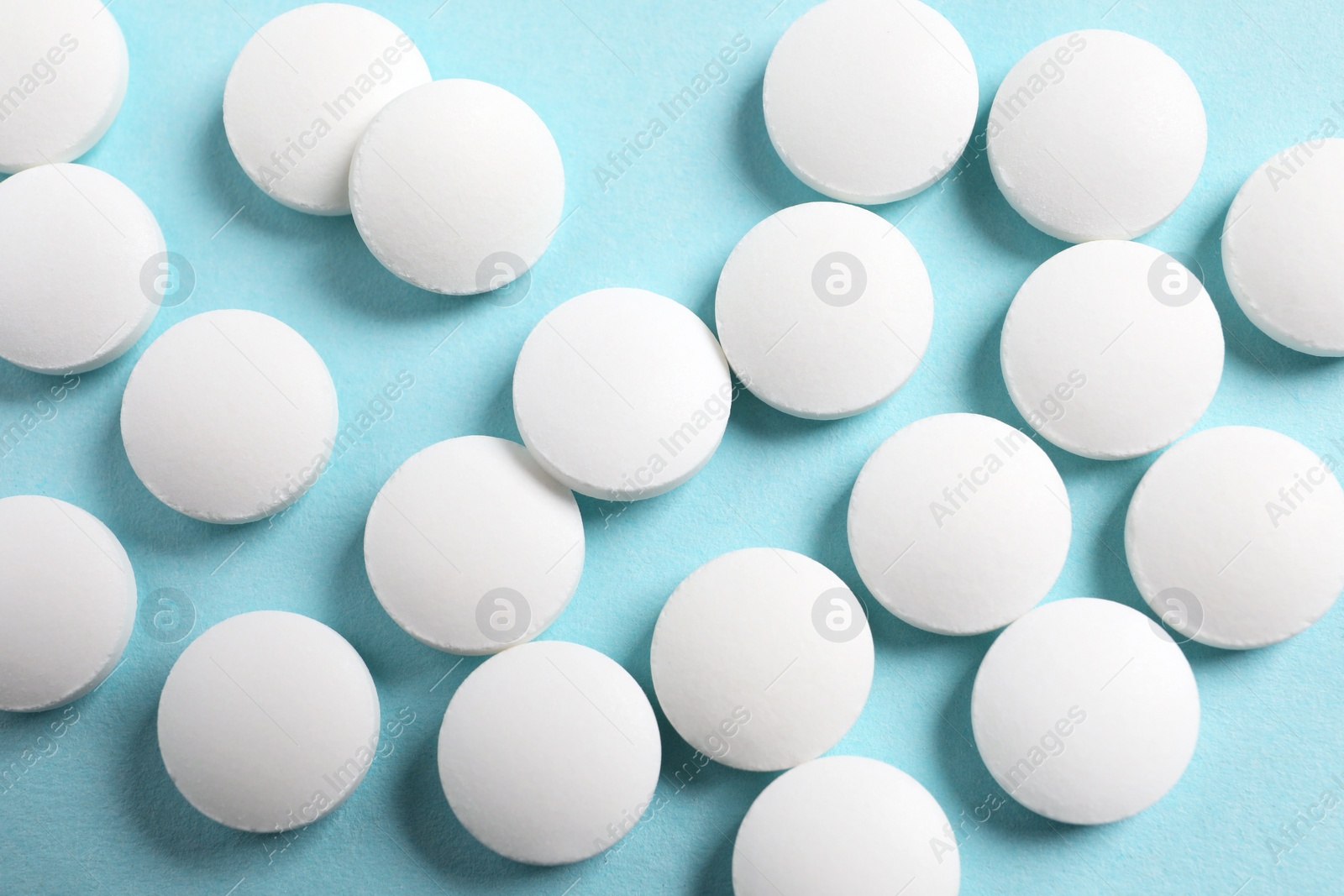 Photo of Many white pills on light blue background, flat lay