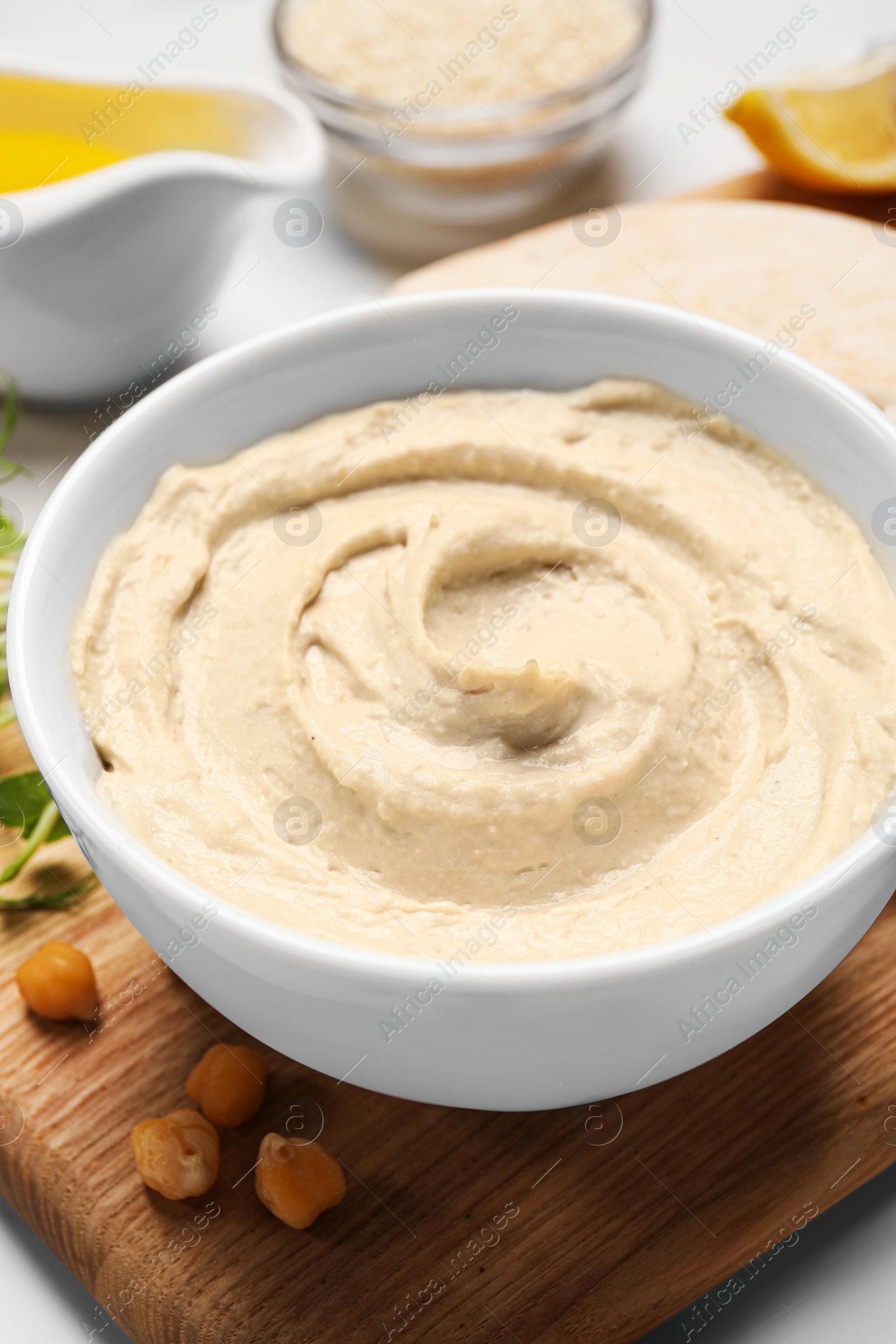 Photo of Delicious hummus and different ingredients on white table