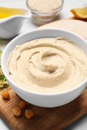 Photo of Delicious hummus and different ingredients on white table