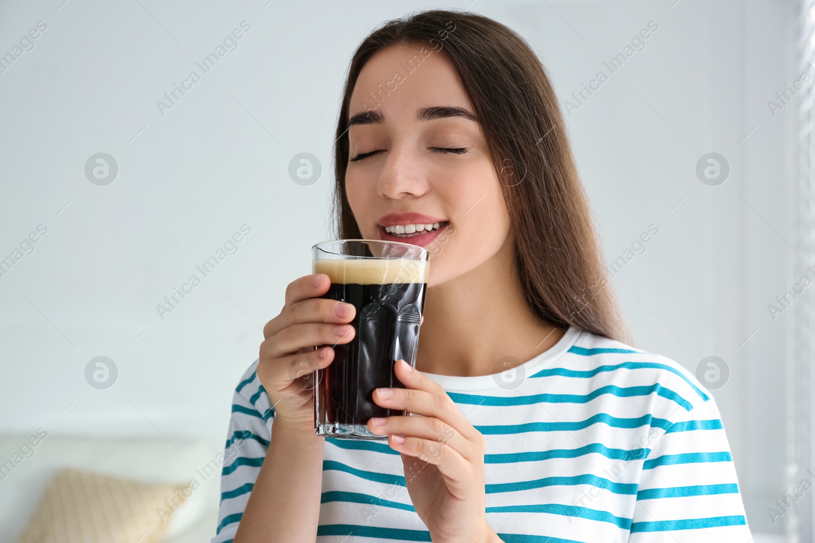 Photo of Beautiful woman with cold kvass indoors. Traditional Russian summer drink