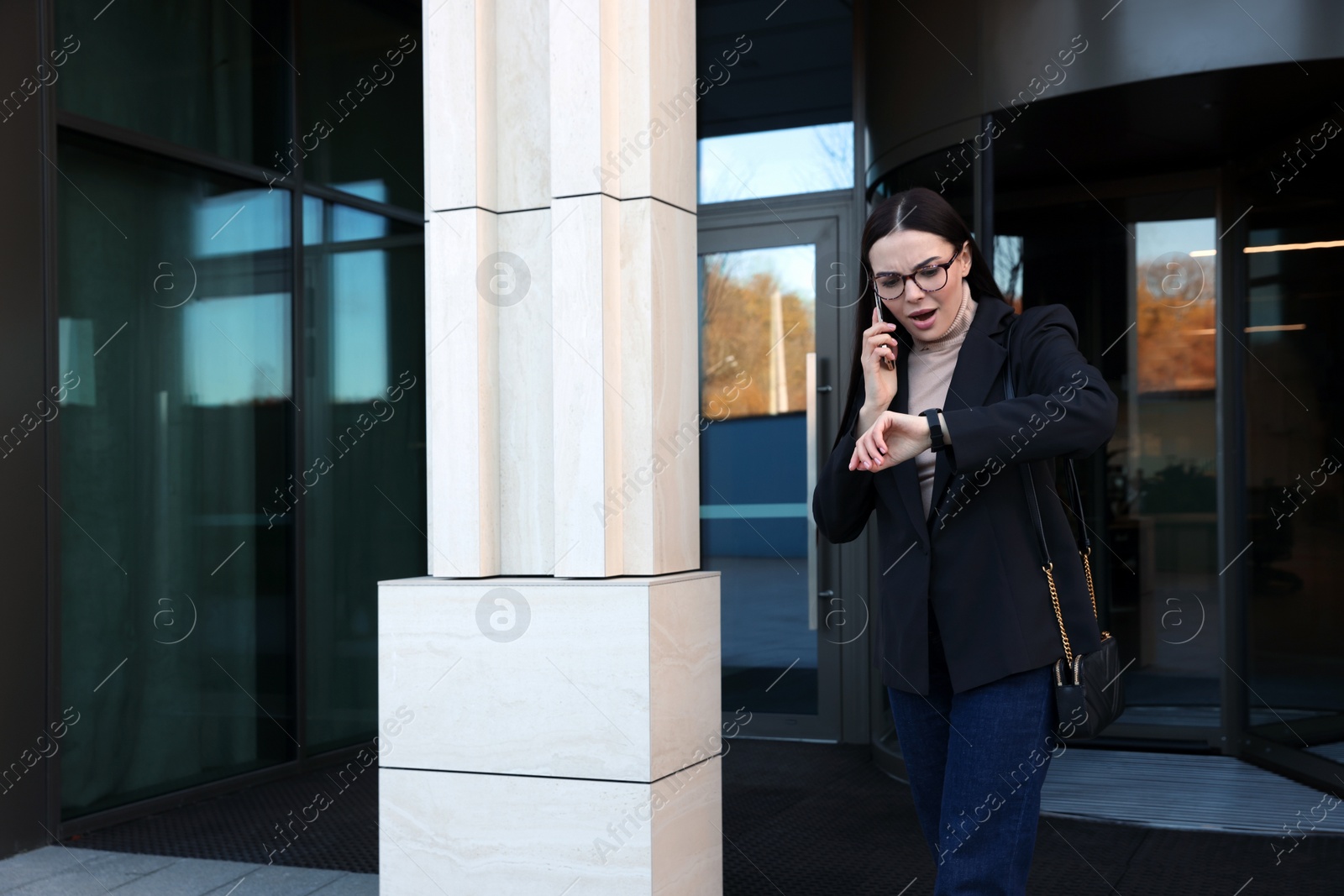 Photo of Emotional woman checking time while talking on smartphone outdoors. Being late concept