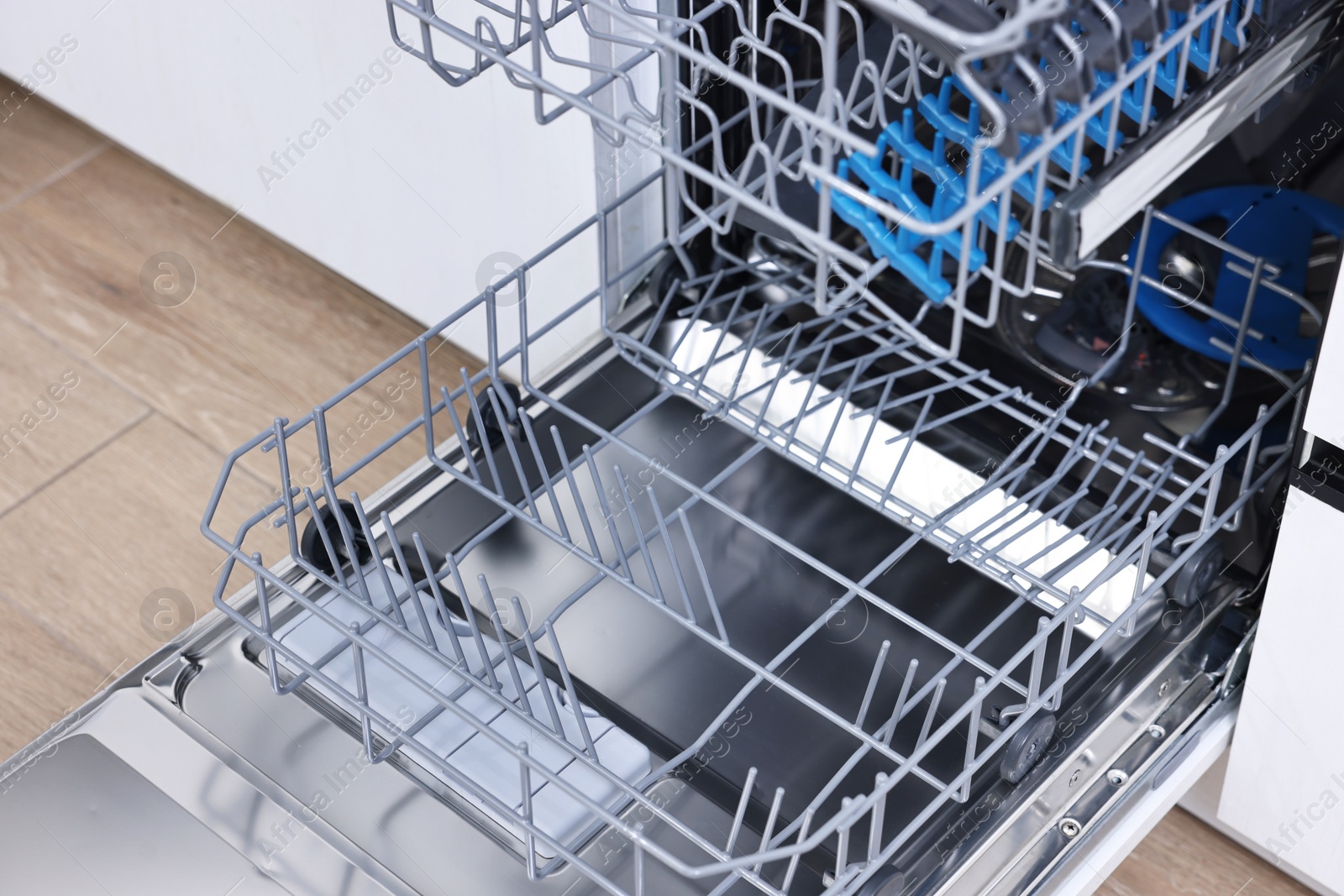 Photo of Open clean empty dishwasher indoors, closeup. Home appliance