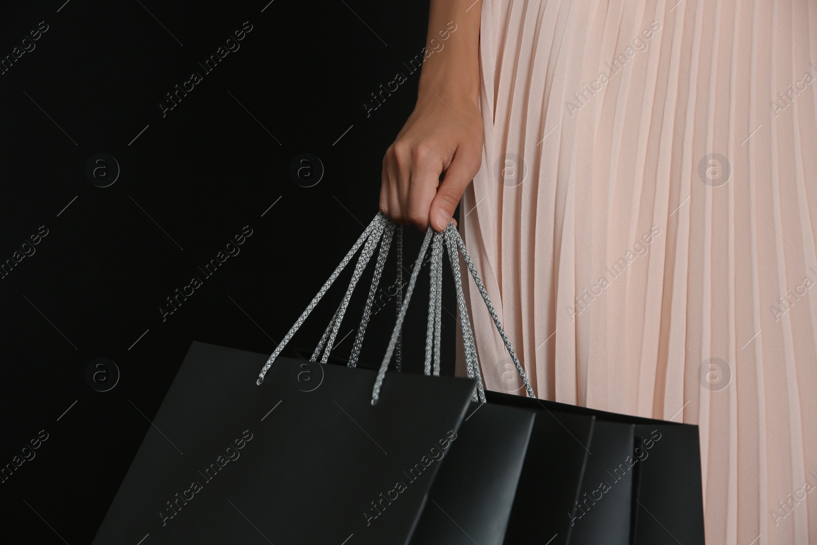 Photo of Young woman with shopping bags on dark background, closeup. Black Friday Sale