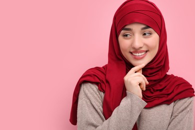 Portrait of Muslim woman in hijab on pink background, space for text