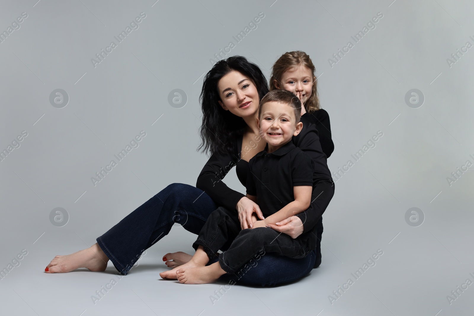 Photo of Little children with their mother on grey background