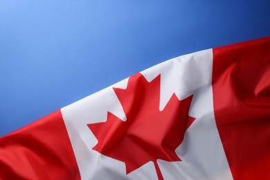 Photo of Flag of Canada on blue background, top view. Space for text