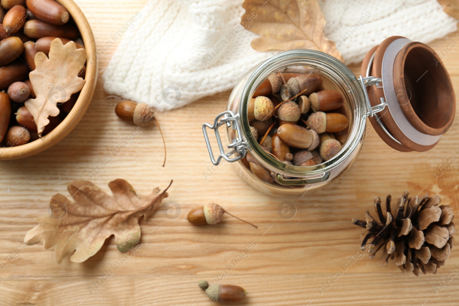 Photo of Acorns, oak leaves and pine cone on wooden table, flat lay