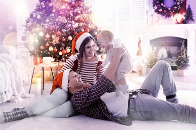 Happy family with cute baby on floor in room decorated for Christmas. Magical festive atmosphere