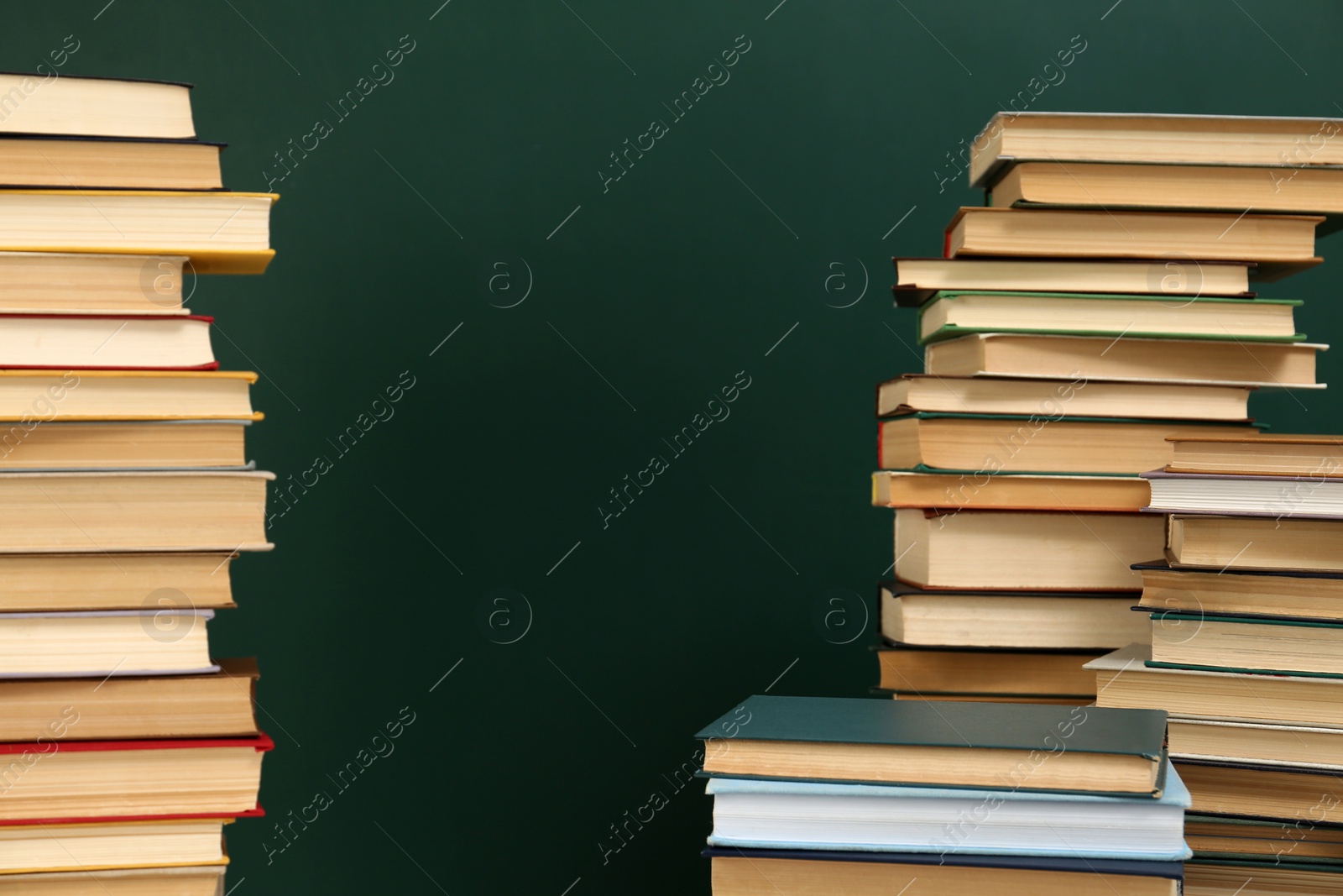 Photo of Many hardcover books near green chalkboard, space for text. Library material