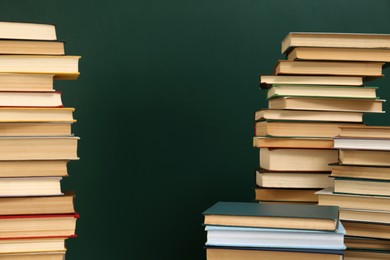 Photo of Many hardcover books near green chalkboard, space for text. Library material