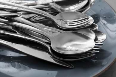 Photo of Silver clean spoons, forks and knives on plate, closeup