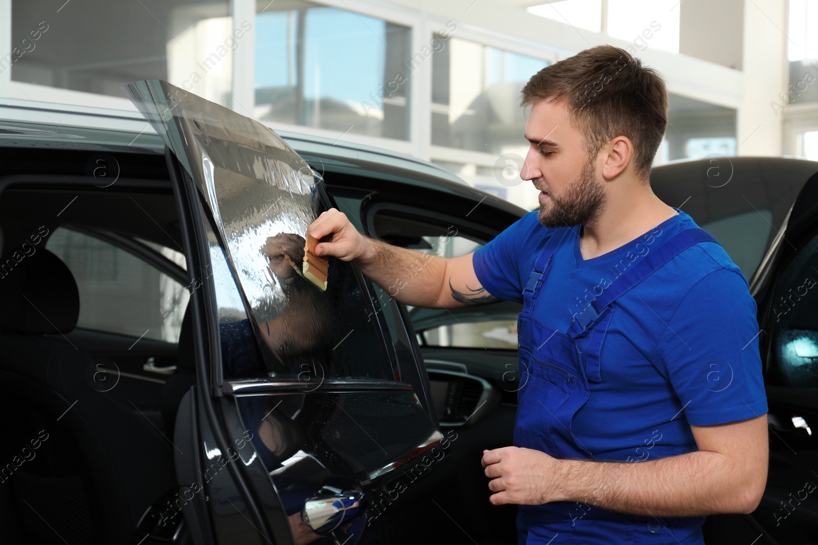 Photo of Worker tinting car window with foil in workshop