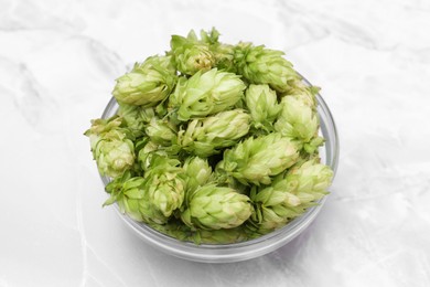 Photo of Bowl of fresh green hops on light grey marble table, closeup