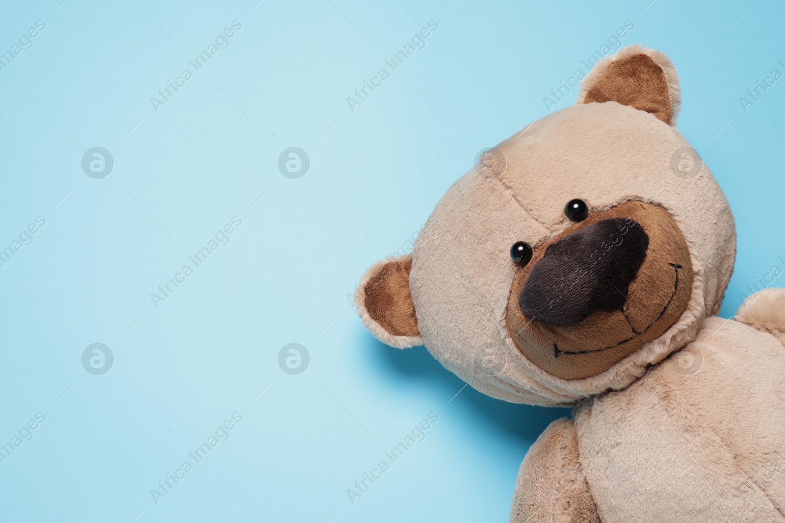 Photo of Cute teddy bear on light blue background, top view. Space for text