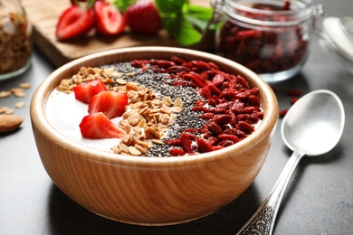 Photo of Smoothie bowl with goji berries and spoon on grey table