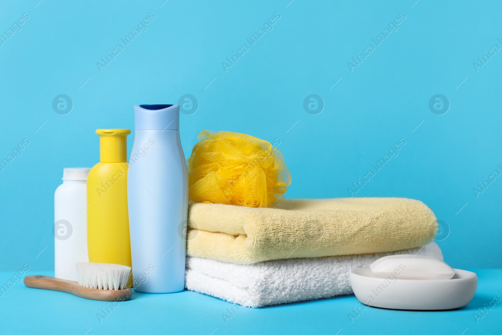 Photo of Baby cosmetic products, accessories and towels on light blue background