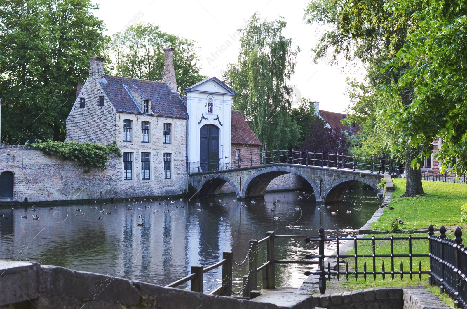 Photo of BRUGES, BELGIUM - JUNE 14, 2019: Bridge over canal and entrance gate to the Princely Beguinage Ten Wijngaerde