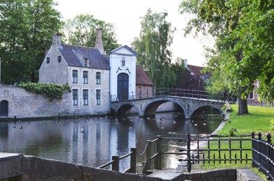 Photo of BRUGES, BELGIUM - JUNE 14, 2019: Bridge over canal and entrance gate to the Princely Beguinage Ten Wijngaerde