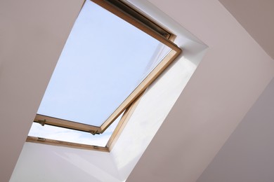 Open skylight roof window on slanted ceiling in attic room