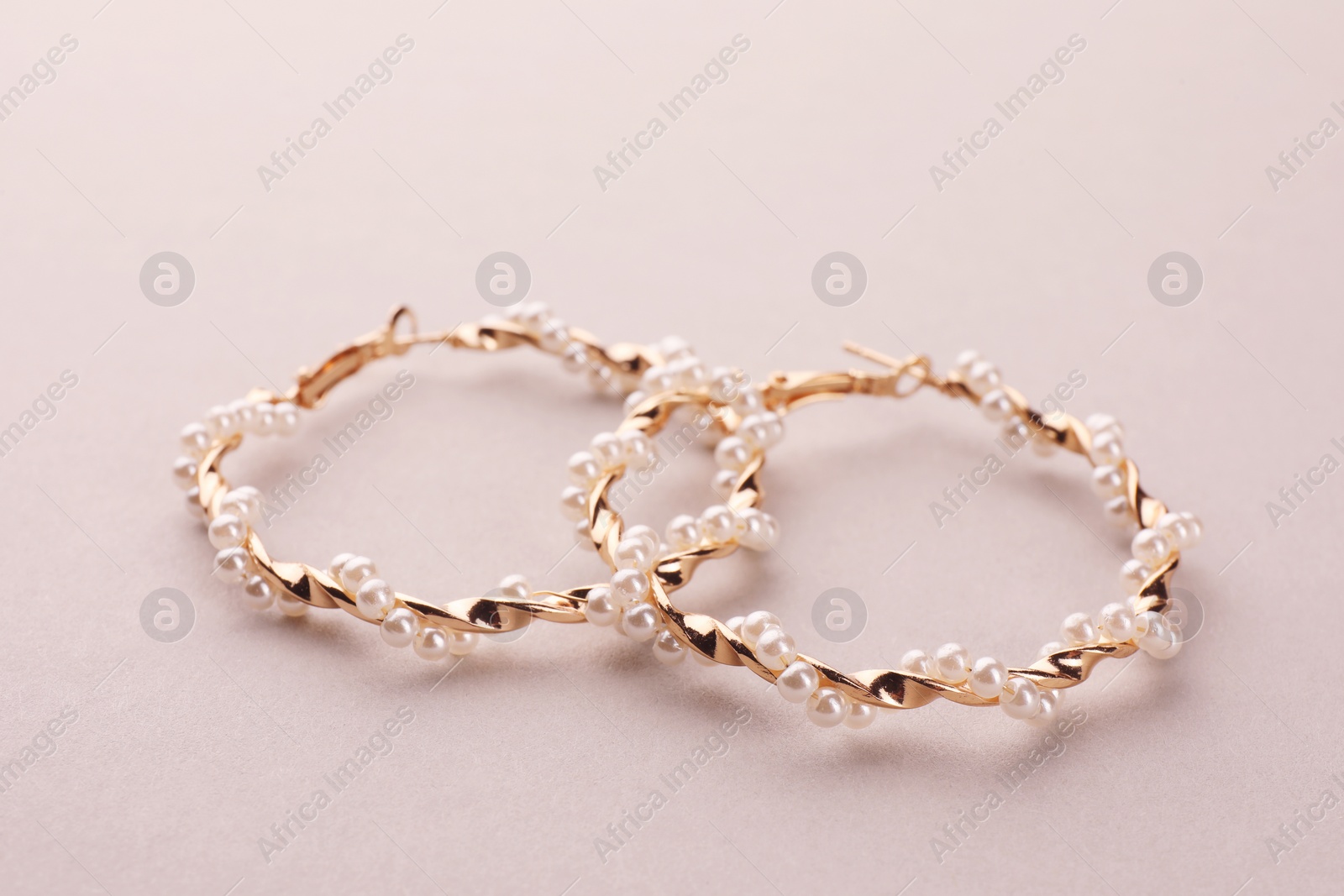 Photo of Elegant earrings with pearls on beige background