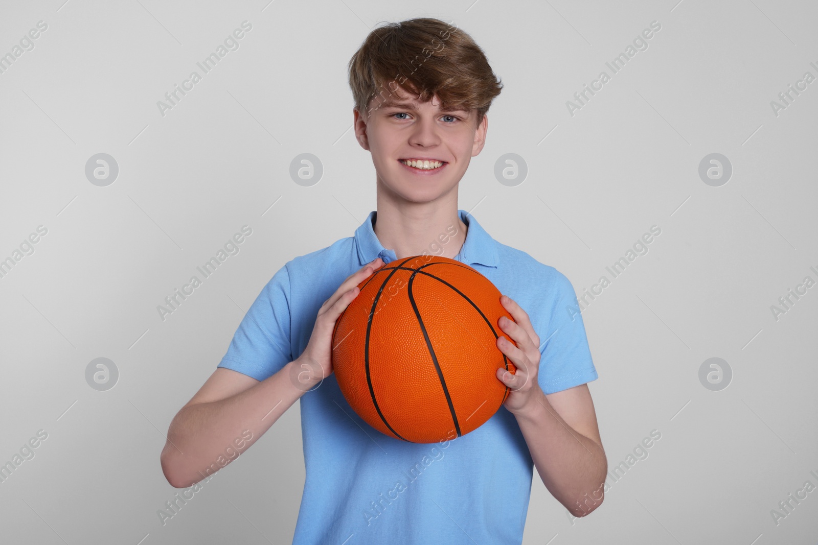 Photo of Teenage boy with basketball ball on light grey background