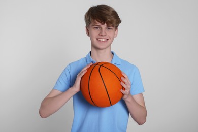 Photo of Teenage boy with basketball ball on light grey background