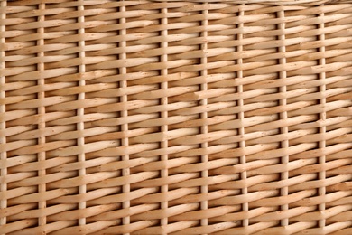 Handmade wicker basket made of natural material as background, closeup view