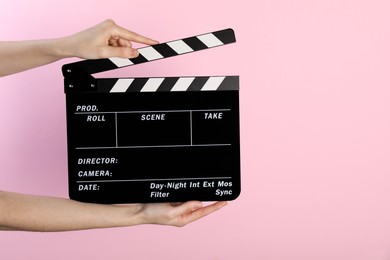 Photo of Woman holding movie clapper on pink background, closeup. Space for text